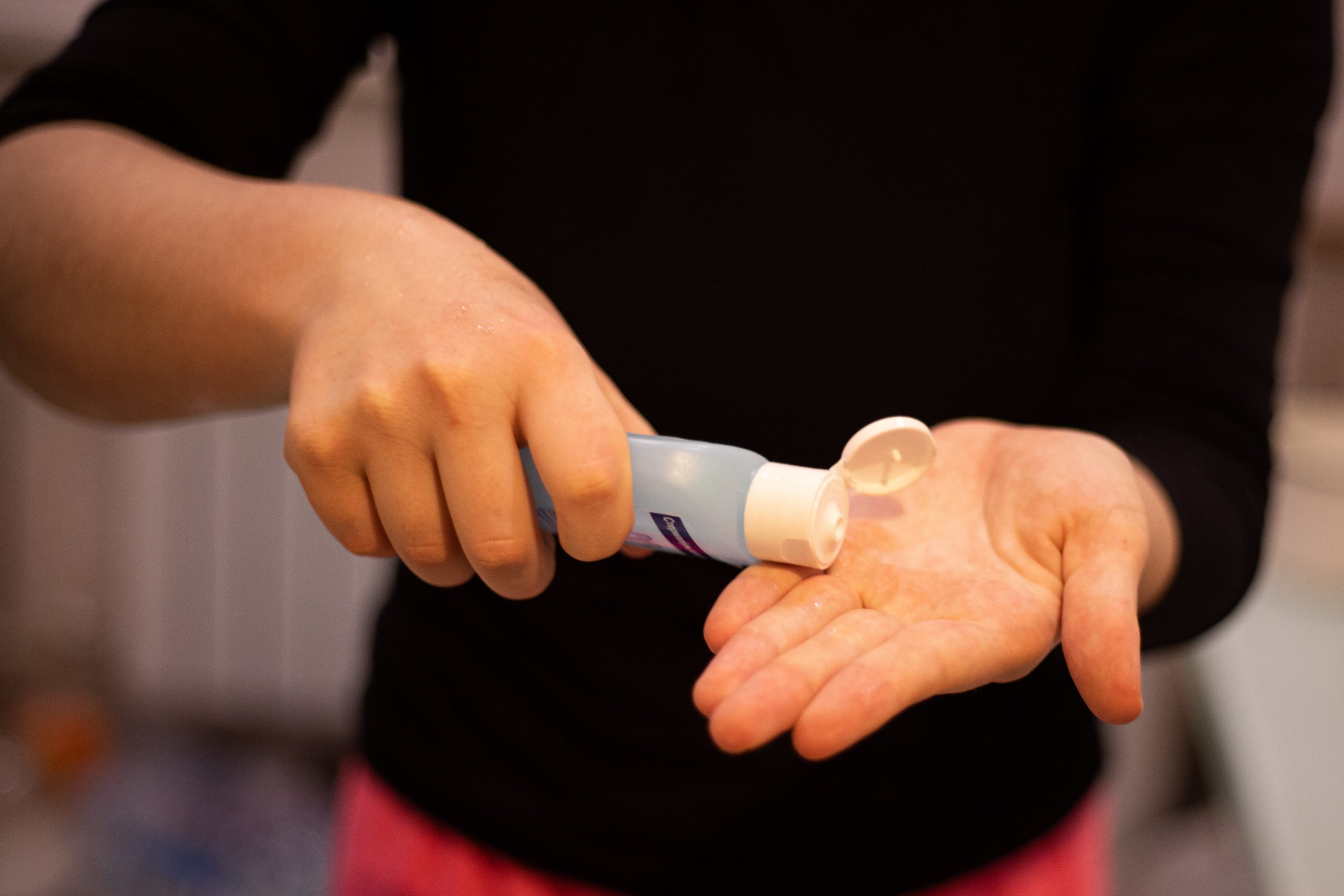 Image of person putting on hand sanitizer. Please sanitize hands to prevent the spread of COVID-19.